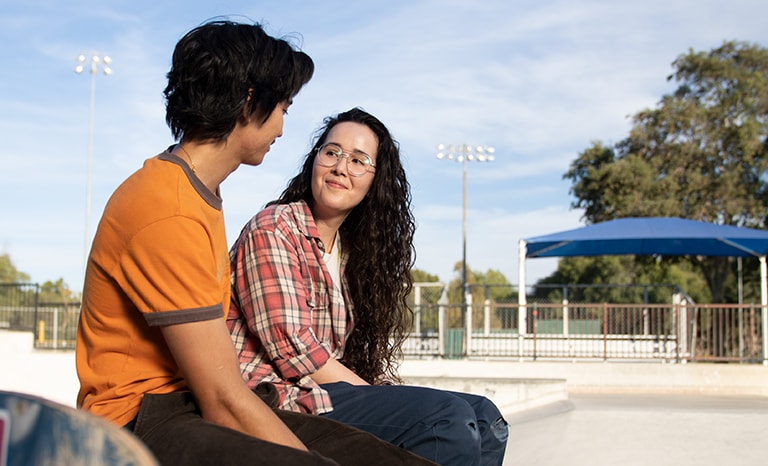 Female-male-talking-outside Female and male talking outside at skatepark